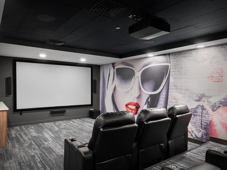 a screening room with black leather chairs and a large mural on the wall